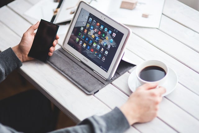 Lap top, cell phone and a cup of coffee on a table