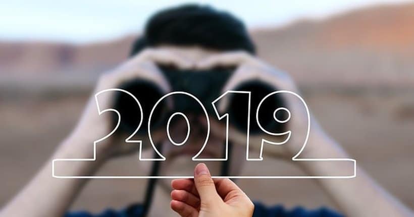 Young man looking through binoculars at 2019